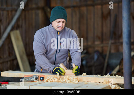 Woodworking - man using hand planer on a pine wood Stock Photo