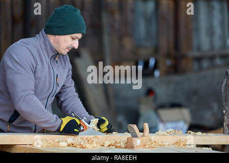 Woodworking - man using hand planer on a pine wood Stock Photo