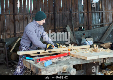 Woodworking - man using hand planer on a pine wood Stock Photo