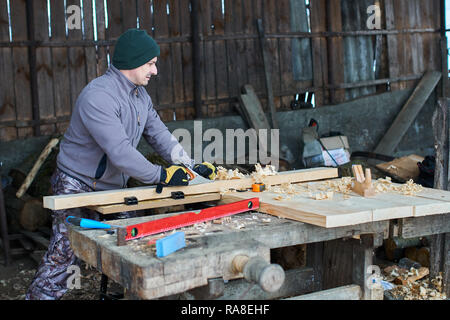 Woodworking - man using hand planer on a pine wood Stock Photo