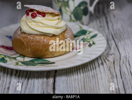 One Semla Cake with Cranberries on Dish on wooden table background Stock Photo
