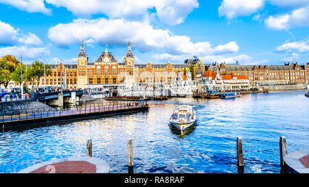 The famous Central Station with the Tourist Canal Boats in the Oosterdok Canal in the city center of Amsterdam in the Netherlands Stock Photo