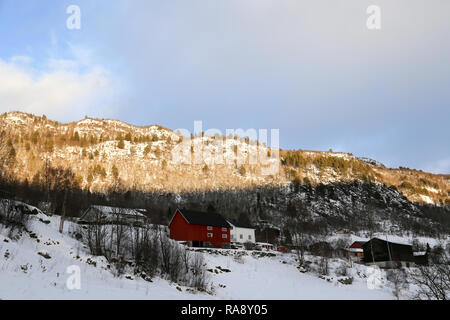 Sun shining on snowy mountain side with cabin Stock Photo