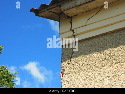Architecture detail of damaged house corner dilapidated old building facade wall over blue sky background. Private abandoned home fall to ruin. Exteri Stock Photo