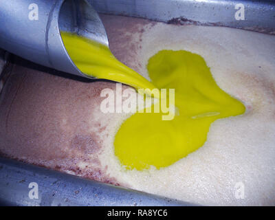 Making oil Olive oil falling into a metal decanter inside an oil mill Stock Photo