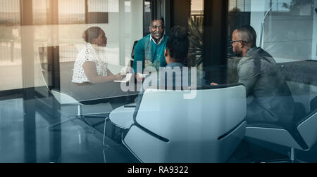 Team of african bussines people talking during an work meeting shot through a glass window, looking into the boardroom Stock Photo