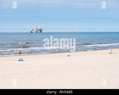 People on beach and North Sea with offshore drilling platform, West Frisian island Ameland, Friesland, Netherlands Stock Photo