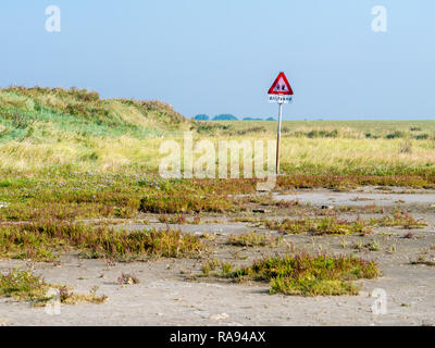 Warning sign for dangerous quicksand in salt marshes of coast of West Frisian island Schiermonnikoog at low tide of Wadden Sea, Netherlands Stock Photo