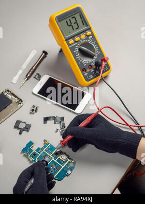 Technician or engineer using digital multimeter to electric current measurement on smartphone logic board for diagnosis broken smartphone Stock Photo