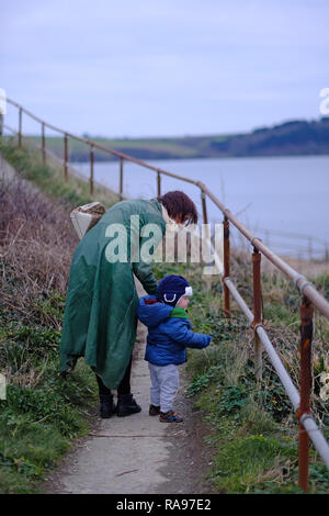 A mother and her son walking along a path by the sea in winter in Cornwall, UK Stock Photo