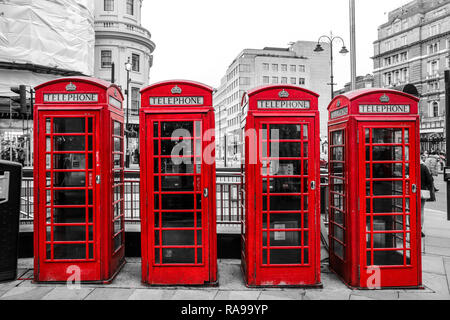 Four traditional British red telephone boxes are standing on the street.   Booth are isolated in a black and white picture Stock Photo
