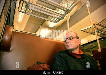 Middle age man looking out of the window of train. Passenger during travel by high speed express train in Europe. Elderly man travelling in train at night Stock Photo