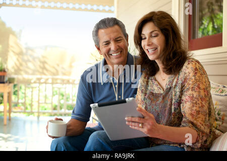 Couple looking at an ipad on their verandah. Stock Photo
