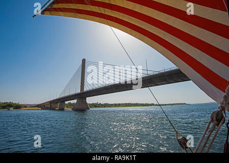 Large luxury traditional Egyptian dahabeya river boat with striped sail on the Nile under cable stayed bridge Stock Photo