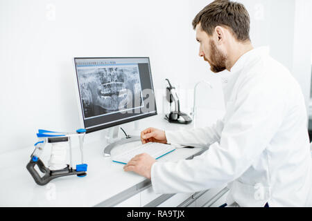 Dentist looking on the x-ray of a jaw working with a computer in the dental office Stock Photo