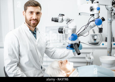 Portrait of a male dentist during the examination with professional microscope at the surgery dental office Stock Photo