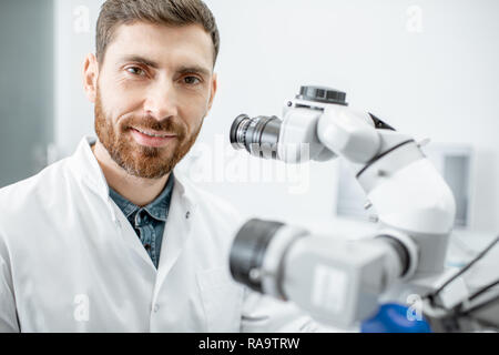 Portrait of a male dentist during the examination with professional microscope at the surgery dental office Stock Photo
