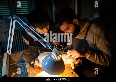 pair of craftsmen violin maker while working on a new violin in the workshop Stock Photo