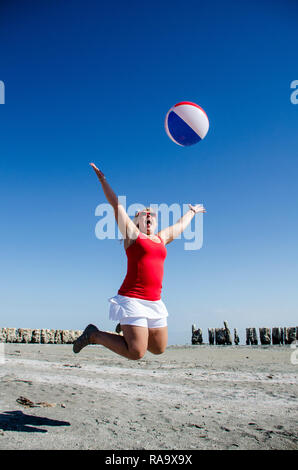 A woman jumps with a beach ball at the Salton Sea, California's biggest lake in the ghost town of Bombay Beach Stock Photo