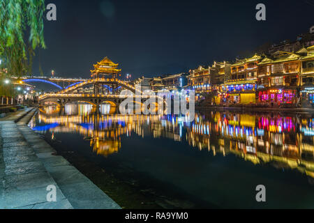 Colorful bridge reflected in water at night, Fenghuang ancient town Stock Photo