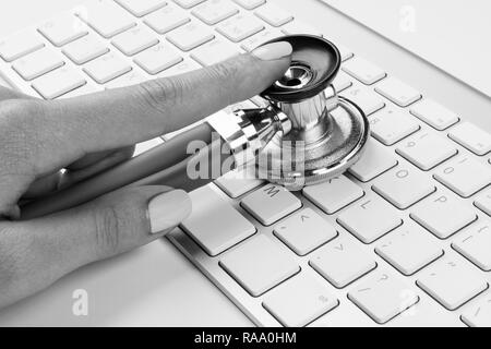 technician female (woman) hand using stethoscope for examines computer keyboard, computer service concept, computer and internet maintenance, checking Stock Photo