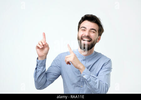 Middle age man smiling with happy face looking and pointing to the side with finger Stock Photo