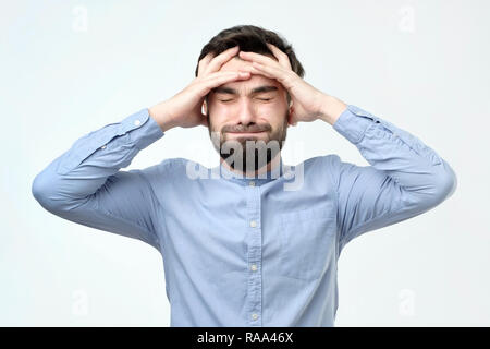 Young unhappy businessman holds his head, stress, headache and frustration concept Stock Photo