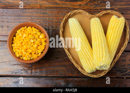 Corn cob, fresh, harvested from plantation inside basket with heart shape on rustic wooden table. space for text Stock Photo