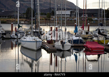 Various size private sailing mast yachts, vessels and boats moored to the floating wooden pier in the Hood River Bay on the Columbia River with reflec Stock Photo