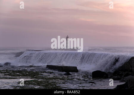 Sea wave water flowing over pier at sunset or dusk. Ave river pier and beacon mouth, north of Portugal. Stock Photo