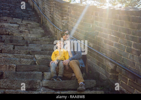 Happy cheerful joyful tourists dad and son at Great Wall of China having fun on travel smiling laughing and dancing during vacation trip in Asia. Chinese destination. Travel with children in China concept Stock Photo