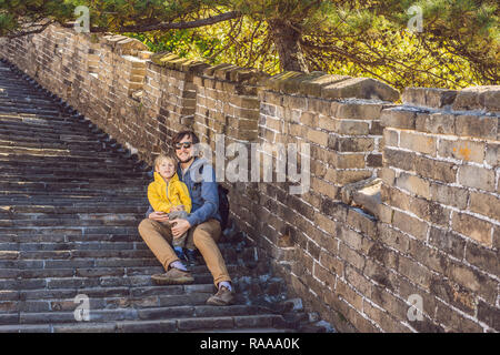 Happy cheerful joyful tourists dad and son at Great Wall of China having fun on travel smiling laughing and dancing during vacation trip in Asia. Chinese destination. Travel with children in China concept Stock Photo