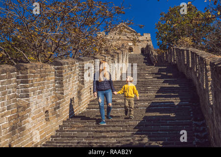 Happy cheerful joyful tourists mom and son at Great Wall of China having fun on travel smiling laughing and dancing during vacation trip in Asia. Chinese destination. Travel with children in China concept Stock Photo