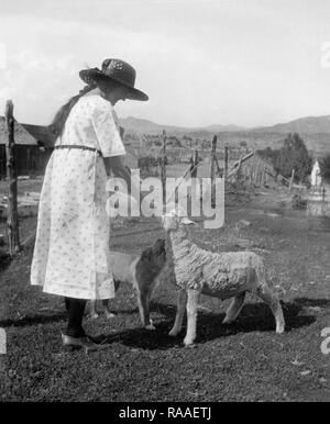 A woman hand feeds a lamb on a Colorado farm, ca. 1928. Stock Photo