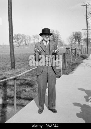 A man with a bowler hat gestures happily, ca. 1930. Stock Photo