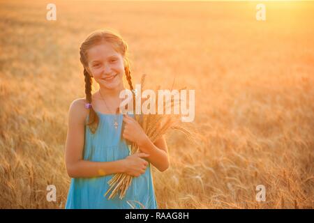 young girl joys on the wheat field at the sunset time Stock Photo