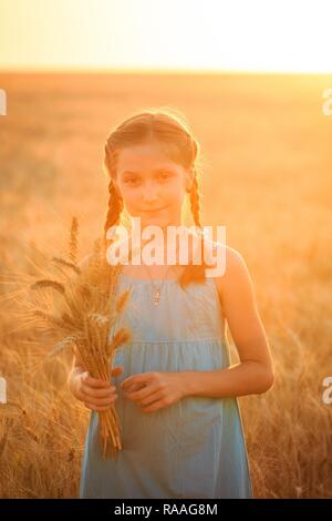 young girl joys on the wheat field at the sunset time Stock Photo