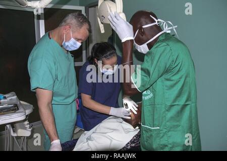 A team of U.S. military and Senegalese medical professionals examine a dental patient during Medical Readiness Training Exercise 17-1 at La Sante des Armees Hospital in Dakar, Senegal, Jan. 12, 2017. MEDRETE is a combined effort between the Senegalese government, U.S. Army Africa, the U.S. Army Reserve 332nd Medical Brigade in Nashville, Tenn., and the Vermont Air National Guard. AFRICOM’s MEDRETEs hosted by United States Army-Africa pair small teams of military medical professionals from the U.S. with participating African partner nations to train alongside and share best practices in trauma  Stock Photo