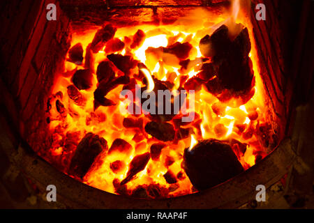 An open fire burning in wintertime. Ebmers glow bright within the hearth. Stock Photo