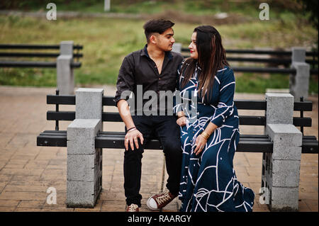 Portrait of a smiling young couple sitting on the bench outdoors and  looking at camera Stock Photo - Alamy