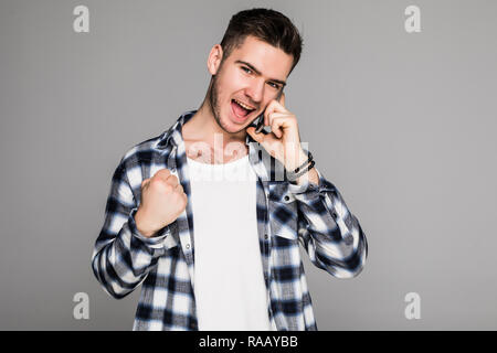Young handsome man speaking on the phone over isolated background screaming proud and celebrating victory and success very excited, cheering emotion Stock Photo