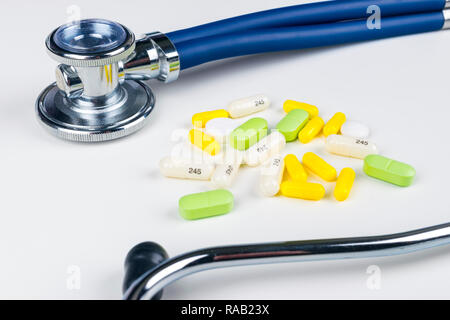 Medical stethoscope lying on white table with pile of pills. Cardiology care health protection prevention and help. Healthy life or insurance concept. Stock Photo