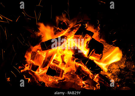 Abstract background with Burning firewood in the fireplace close up, BBQ fire, Sparking charcoal background. Spark of bonfire. Stock Photo