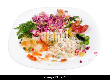 Remains  and scraps of all Christmas salads on one plate. Isolated on white studio macro shot Stock Photo