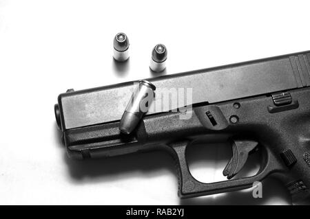 A black semi automatic 9mm pistol on a white background with three hollow point bullets shown in black and whtie Stock Photo