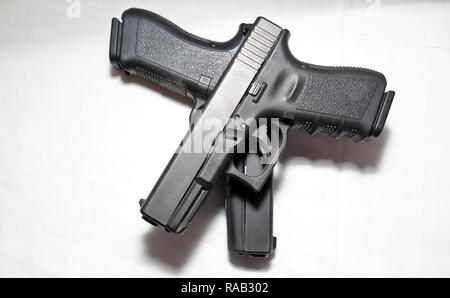 Two black semi automatic pistols, a 9mm and a 40 caliber with one on top of the other on a white background Stock Photo