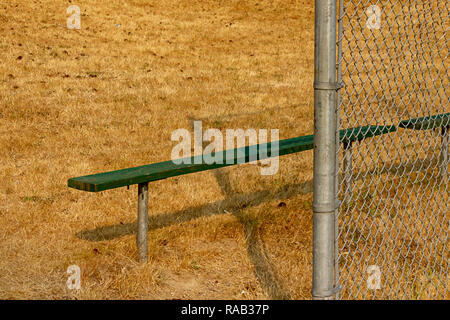 green bench on edge of summer ball field  Stock Photo