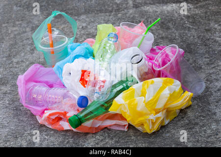Colorful plastic waste, bags, cups, bottles, straws on cement floor background Stock Photo