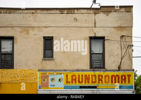 An old, faded but still colorful, laundromat sign in Brooklyn, New York City, USA Stock Photo