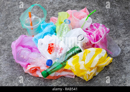 Colorful plastic waste, bags, cups, bottles, straws on cement floor background Stock Photo